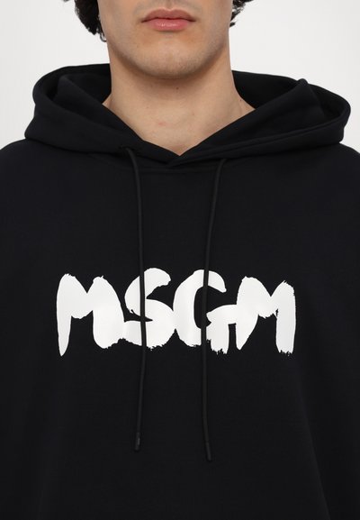 Felpa nera con cappuccio caratterizzata da un grande logo "MSGM" in bianco, stile pennellata, sul davanti. È dotata di coulisse e tessuto testurizzato.