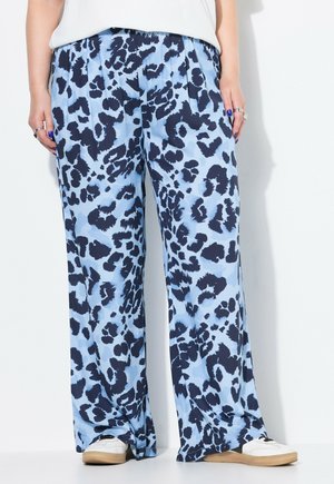 Pantaloni larghi di colore blu chiaro con un motivo a stampa leopardata navy, realizzati in un tessuto morbido con vita elastica. Sneakers bianche visibili.