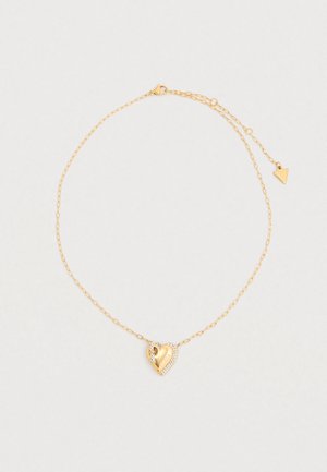 Collier ton doré avec un pendentif en forme de cœur orné d'un petit cristal et d'une gravure de marque, attaché à une chaîne délicate.