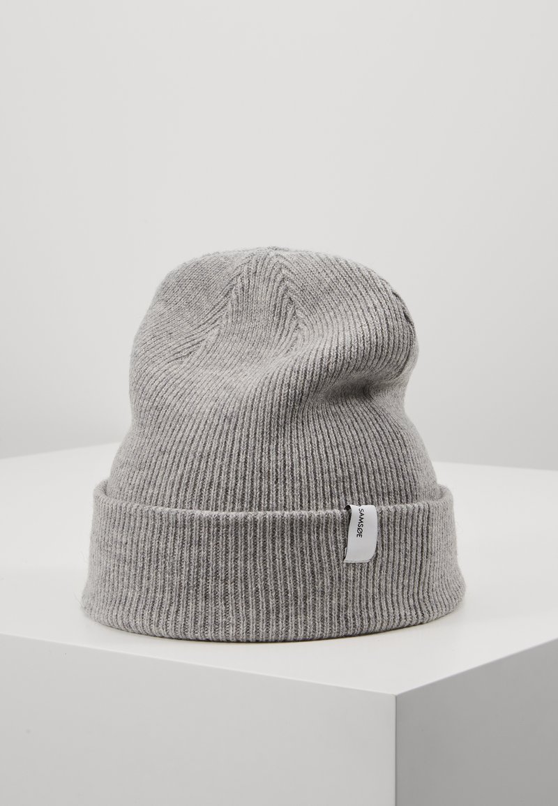 Gray knit beanie with a ribbed texture, a folded cuff, and a small brand tag on the side. Smooth fabric and soft appearance.