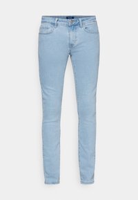 Jeans ajustados de color azul claro con bolsillos frontales, pasadores para cinturón y un cierre de botón sobre un fondo blanco.