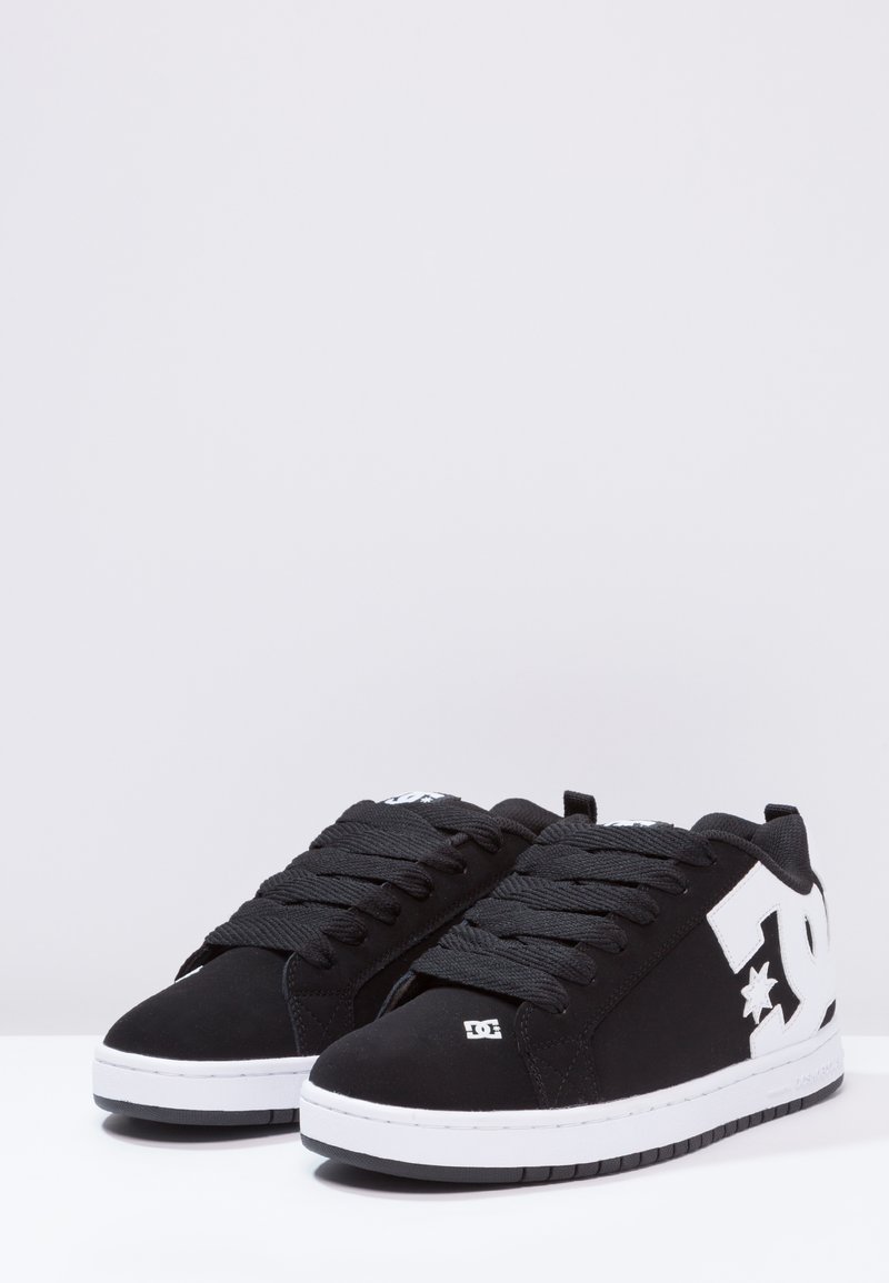 Zapatillas negras con una parte superior de tela suave, que cuentan con cordones negros gruesos, un acento de logo blanco y una suela de goma blanca para mayor tracción.