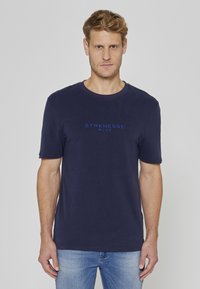 T-shirt en coton bleu marine à manches courtes et col rond. Sur le devant, le texte "STRENESSE BLUE" est imprimé en bleu contrastant.