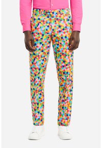 Pantaloni colorati a fantasia con motivo a pois in rosa, giallo, verde e blu, realizzati in un tessuto leggero, abbinati a scarpe da ginnastica bianche.