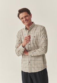 Cămașă cu mânecă lungă și guler căptușit, în carouri bej și maro. Are guler punctat, manșete cu nasturi și un mic logo brodat.