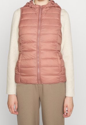 Mouwloos gestoofd roze doorgestikt pufferbodywarmer met ritssluiting aan de voorkant, gedragen over een crème top met lange mouwen en beige broek.