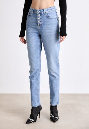 Ljusblå hökvalitetsjeans med femknappsframslutning, rak benform och subtila blekningar. Bärs med svarta högklackade stövlar.