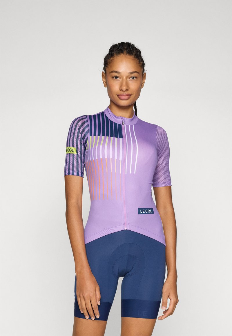 Maglia da ciclismo viola a maniche corte, con strisce diagonali in blu navy, verde e arancione. Abbinata a pantaloni corti blu scuro. Tessuto resistente.