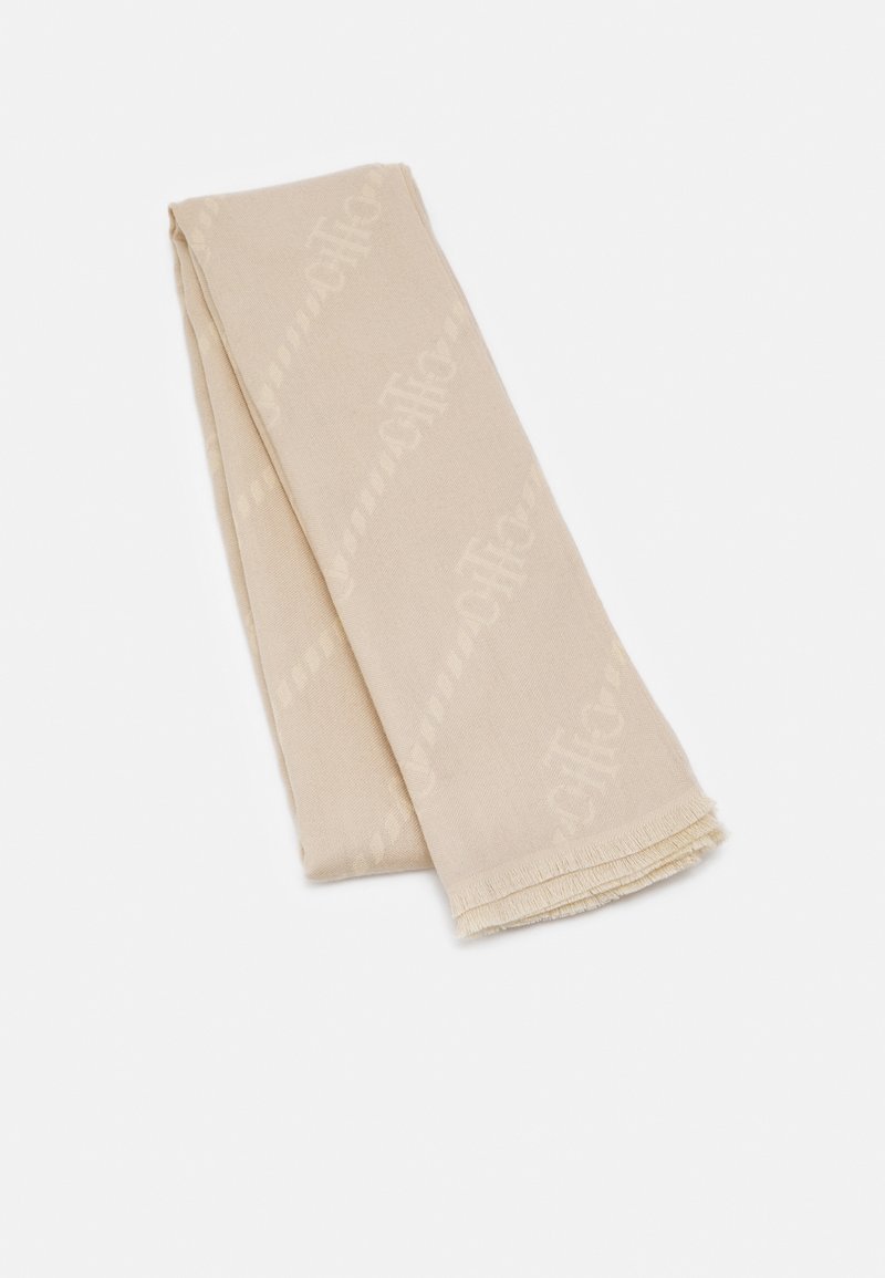 Écharpe tissée beige avec un motif texturé ton sur ton subtil et des franges courtes à une extrémité, pliée sur un fond blanc uni.