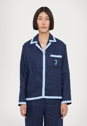 Marineblå bomulds pyjamasoverdel med lyseblå krave og lomme trim, med en dekorativ lomme lap og knaplukning.