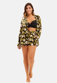 Ensemble de pyjama à imprimé floral noir, comprenant une chemise à manches longues et un short, avec une texture lisse et une taille à cordon. Soutien-gorge en dentelle noir en dessous.