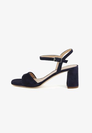 Sandali con tacco in suede blu navy, con tacco a blocco e cinturino alla caviglia, dotati di punta aperta arrotondata e texture morbida.