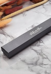 Scatola di gioielli rettangolare nera con finitura testurizzata, con scritta in argento "Sofia Milani Jewels." Posizionata su una superficie di marmo.