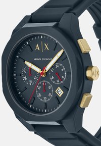 Crni narukvica sat marke Armani Exchange sa zlatnim detaljima, tri crvena podbroja, bijele i zlatne kazaljke te prikaz datuma na 4 sata.