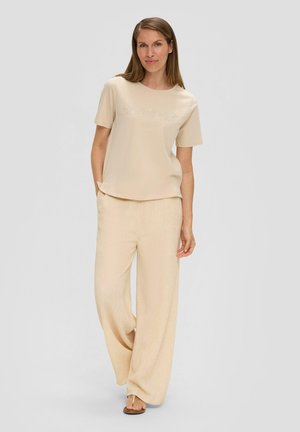 Beige top met korte mouwen met de tekst "Zomer", gecombineerd met lichtbeige wijde broek met een subtiel textuurpatroon.