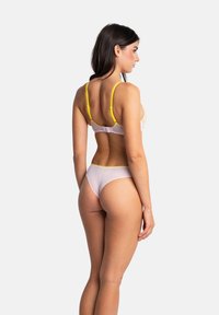 Ensemble de bikini en tissu blanc doux avec des accents jaunes, doté de bretelles ajustables, d'un design en dentelle et d'une coupe taille basse pour le bas.