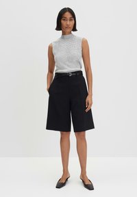 Graues, geripptes, ärmelloses Oberteil kombiniert mit schwarzen, taillierten Shorts mit einem Gürtel. Das Outfit hat ein minimalistisches Design und eine strukturierte Passform.