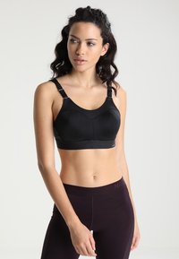 Svart sport-BH med justerbare stropper, en bred kant og en glatt tekstur. Den har en buet utringning og subtile mesh-detaljer.