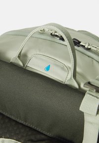 Zaino verde chiaro con manico superiore, tessuto testurizzato e un piccolo logo a goccia d'acqua blu sulla parte anteriore.