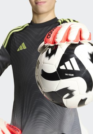Person in schwarz-grünem Adidas-Torwarttrikot hält einen schwarz-weißen Adidas-Fußball mit roten Handschuhen.