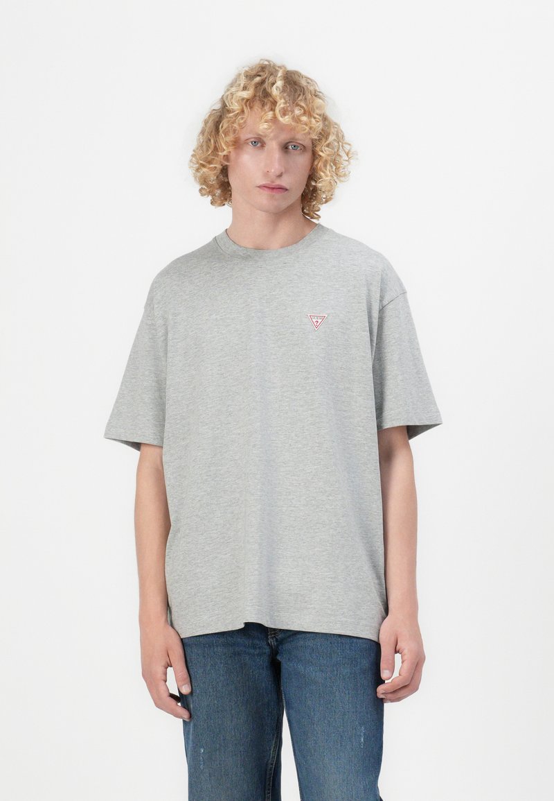 Graues Baumwoll-T-Shirt mit Rundhalsausschnitt, kurzen Ärmeln und einem kleinen roten Dreieckslogo auf der linken Brust. Lockerer Schnitt.