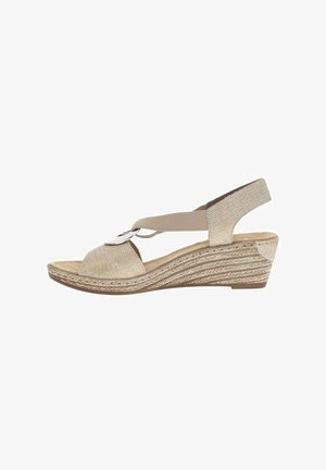 Sandale compensée beige avec bride avant texturée, boucle argentée décorative, lanière élastique à la cheville et talon moyen tissé à motif.