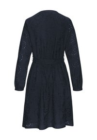 Laulupimeä sininen mekko pitkillä hihoilla, jossa on monimutkaista brodeerausta ja leikattuja kuvioita. Sidottu vyötärö ja liehuva helma.