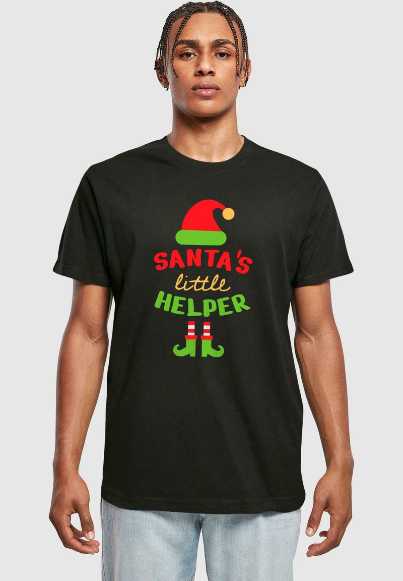 Tricou negru cu textul "MICUL AJUTOR AL LUI MOȘ CRĂCIUN" în culori roșii și verzi, însoțit de un grafic cu o pălărie de elf roșie și verde și pantofi în dungi. Mâneci scurte.