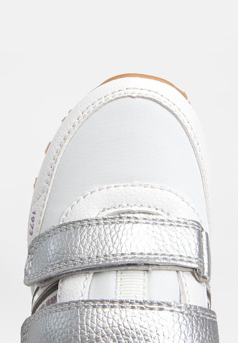 Sneaker bianco con fibbie in Velcro argentato lucido, tessuto testurizzato e dettagli in pelle, punta arrotondata e suola in gomma.