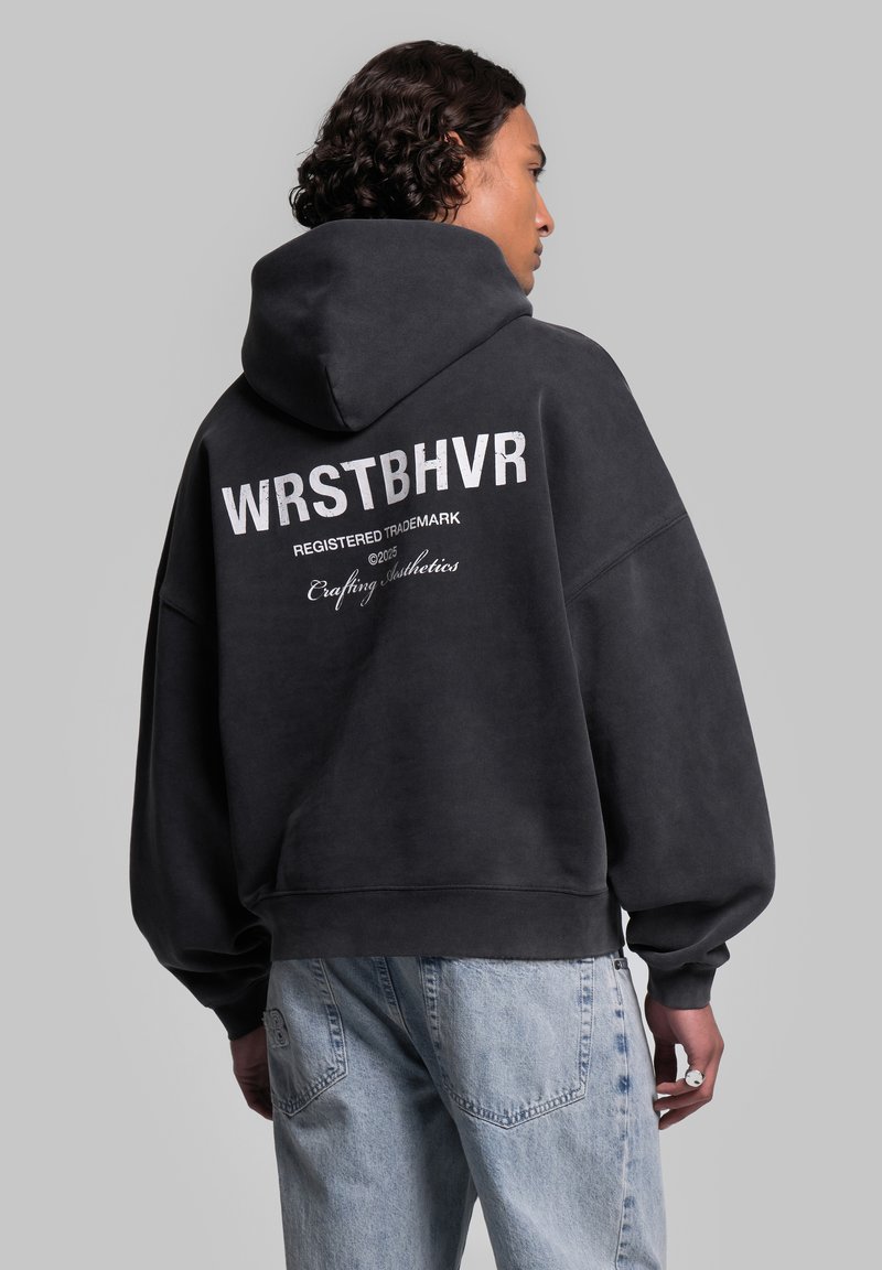 Felpa nera oversize con un grande logo bianco e testo sul retro, caratterizzata da una finitura testurizzata e un cappuccio con coulisse.