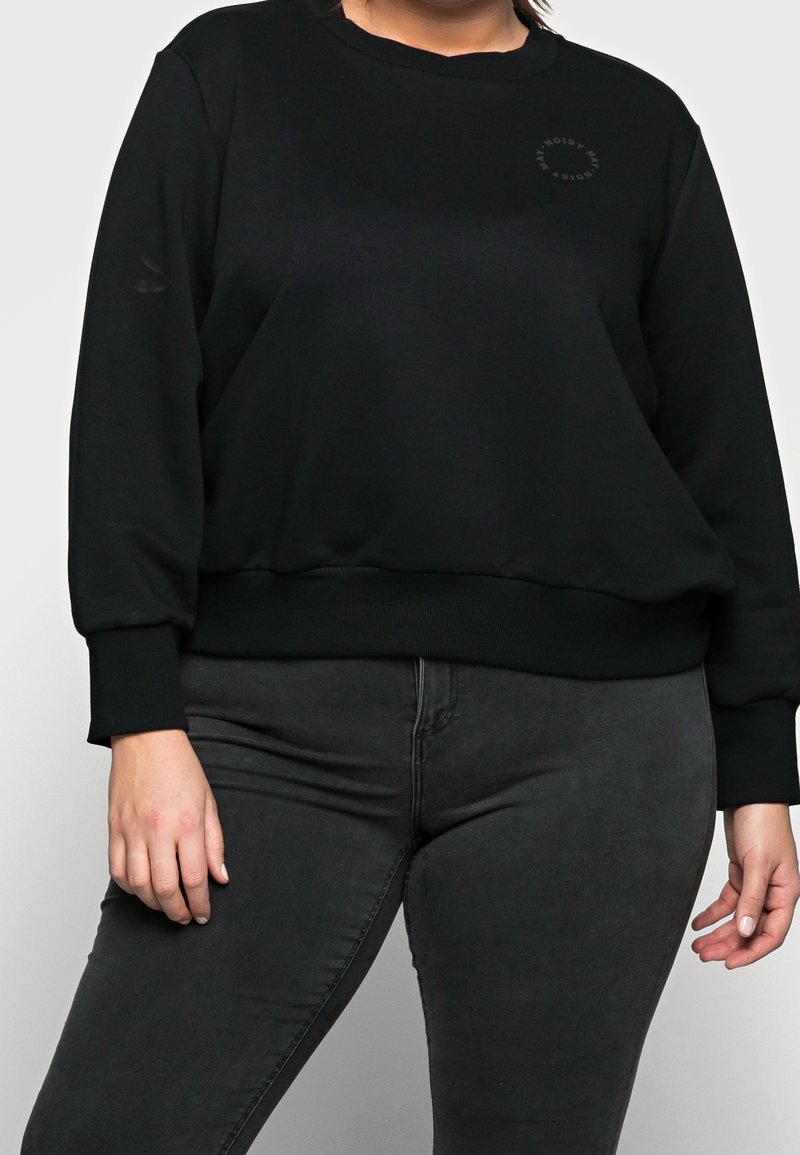 Zwarte sweatshirt met een ronde hals, ribgebreide manchetten en een klein logo-detail. Gepaard met donkergrijze broek voor een gecoördineerde uitstraling.