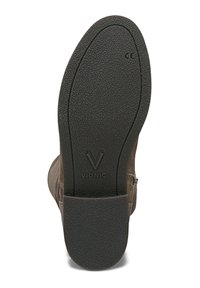 Bottines en cuir brun avec une semelle en caoutchouc noir texturé. Présente un talon plat, une fermeture éclair sur le côté et un logo en relief sur la semelle.