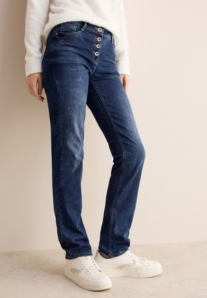 Donkerblauwe denim jeans met een rechte pijp, vijf knopen aan de voorkant en subtiele whiskerdetails, gecombineerd met witte sneakers.