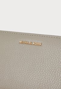 Gray leather wallet featuring a textured surface and a gold embossed "MICHAEL KORS" logo. Stitched edges provide structural detail.