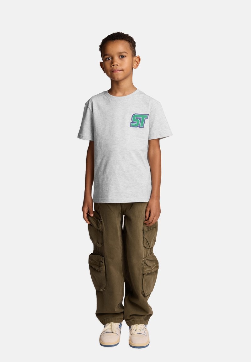 Szara bawełniana koszulka z logo "ST" w zielonym i niebieskim kolorze po lewej stronie klatki piersiowej, zestawiona z luźnymi oliwkowymi spodniami cargo z bocznymi kieszeniami.