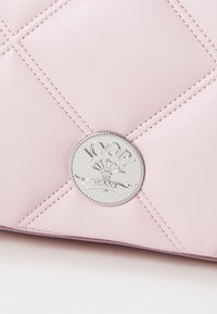 Ljusrosa, vadderad, konstläderväska med en silverfärgad, cirkulär logotyp med "JOOP! JEANS." Utmärkande diagonala sömmar och slät yta.