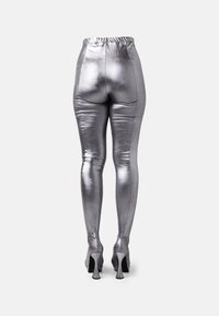 Metallic hopeiset leggingsit, joissa on korkea vyötärö, vartalonmyötäinen muotoilu, sileä pinta ja korostetut saumat, yhdistettynä korkokenkiin.