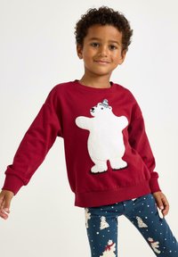 Roter Pulli mit einem plüschigen weißen Eisbären-Design; kombiniert mit navy Leggings, die Eisbären und Schneeflocken auf blauem Hintergrund zeigen.