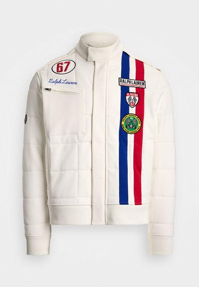 White quilted jacket with high collar, features blue, red, and white stripes, multiple patches, and a front zip pocket.
