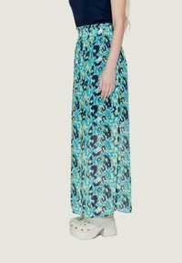 Gonna maxi con un motivo astratto multicolore blu e verde. Tessuto morbido e leggero con vita elastica. Abbinata a zoccoli bianchi.