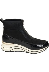 Botte noire à la cheville avec fermeture éclair, fabriquée en matériaux lisses et texturés. Caractéristiques d'une semelle ondulée blanche avec des accents noirs et un bout arrondi.