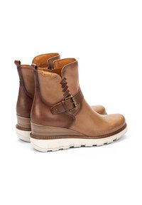 Bottines en cuir marron avec boucle, dotées d'un talon compensé empilé et d'une finition texturée, avec une zone de orteil lisse et des accents en tan contrastants.