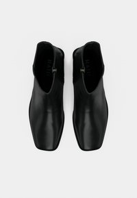 Bottes noires à la cheville en cuir lisse, dotées d'un bout carré, d'une fermeture éclair latérale et d'un design minimaliste sans ornements.