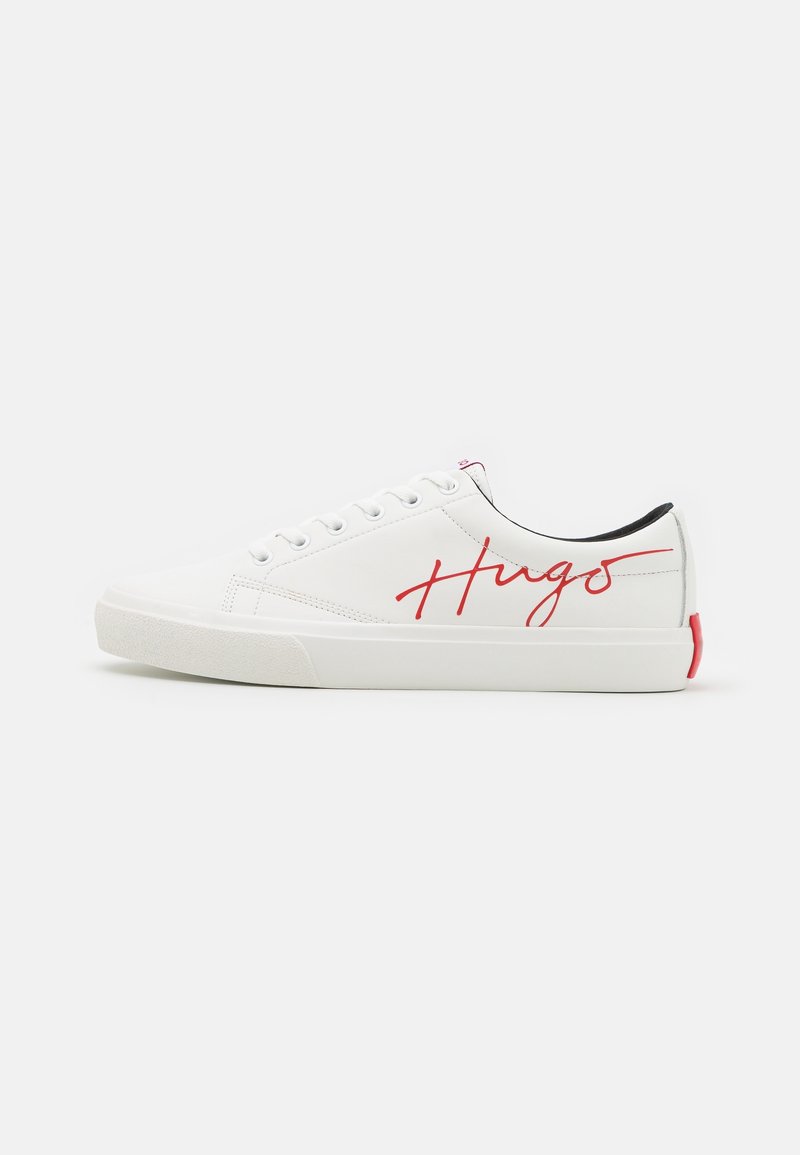Baskets basses blanches avec des lacets blancs, l'inscription rouge "Hugo" sur le côté, une doublure intérieure noire et une languette rouge au talon.