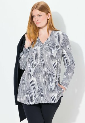 Blusa a maniche lunghe in bianco e nero con motivo astratto a ondulazioni, scollo a V, tessuto morbido, dalla vestibilità ampia e con tasche laterali.
