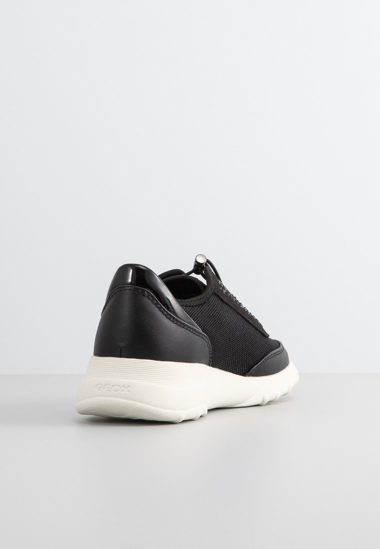 Zapato negro con una parte superior de malla texturada y acentos sintéticos suaves, con una suela blanca y una sutil marca en el talón.