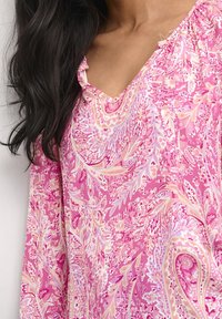 Blusa a maniche lunghe con motivo paisley rosa e scollatura a V. Presenta intricate fantasie floreali e un tessuto morbido e leggero.