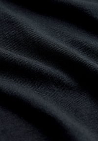 Nahaufnahme eines dunkelblauen Strickstoffes, der eine feine Struktur und subtile Falten zeigt.