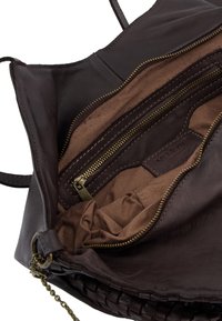 Brązowa skórzana torebka o miękkiej fakturze, z wewnętrzną kieszenią na zamek błyskawiczny, beżowym materiałowym wykończeniem i detalem w plecionym pasku.