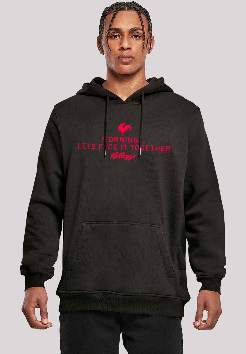 Schwarzer Hoodie mit Kängurutasche; mit rotem Text "MORGEN... LASST UNS DAS GEMEINSAM ANGEHEN" und einem Hahngrafik über "Kellogg's."